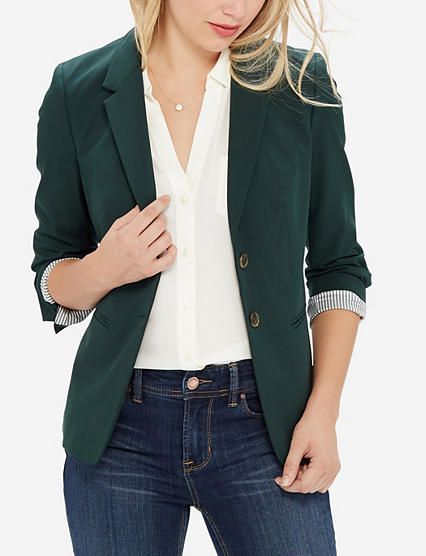 Women's dark green blazer over dark wash jeans and white collared .