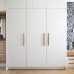 Clean white wardrobe with wooden handles | Bedroom cupboard .