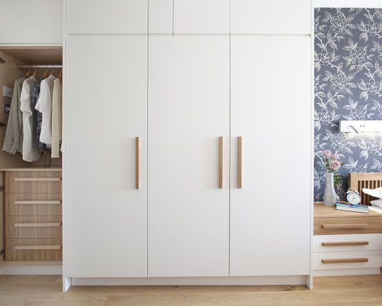 Clean white wardrobe with wooden handles | Bedroom cupboard .