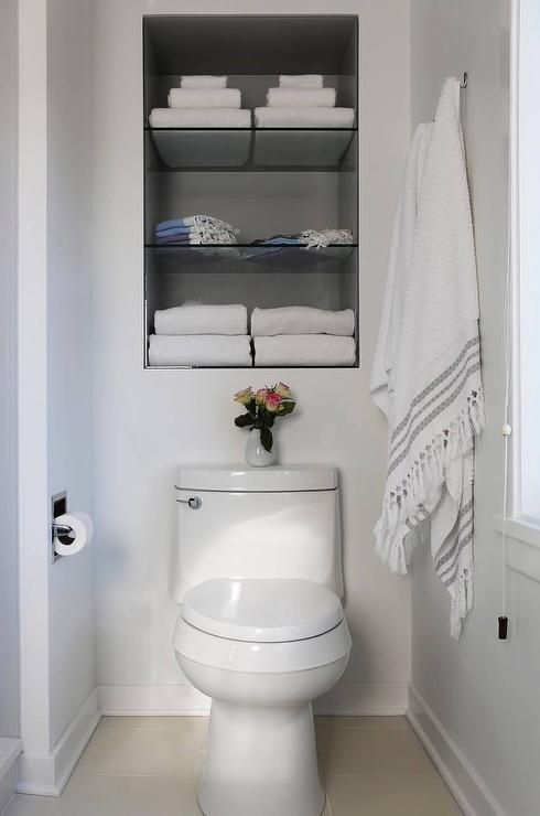 Fantastic bathroom features recessed shelves over the toilet .