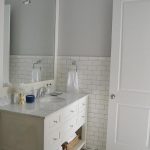White and gray bathroom features top half of walls painted gray .